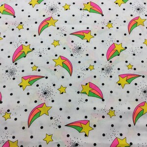 May include: White fabric with a repeating pattern of pink, green, and yellow shooting stars on a white background with black polka dots.