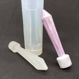 Peut inclure: Un ensemble de trois moules en silicone transparent pour la fabrication de bougies. Les moules sont en forme de cylindre haut, de cylindre bas et de cône pointu. Le moule en forme de cône présente un motif rayé violet et blanc.
