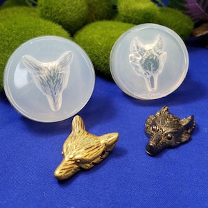 May include: Two clear silicone molds of wolf heads, one with a gold wolf head and one with a black wolf head.