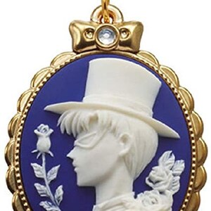 May include: A gold-tone charm featuring a cameo of a man in a top hat and a rose. The cameo is set in a blue enamel oval frame with a gold border.