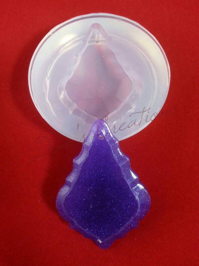 May include: A clear silicone mold for making a purple glitter resin pendant in the shape of a teardrop.