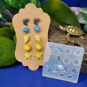 May include: A set of 10 weather-themed earring molds, including a lightning bolt, sun, moon, cloud, and snowflake. The molds are made of clear silicone and are displayed on a brown card with sample earrings.