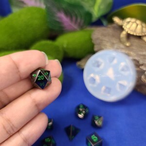 May include: A set of black and green dice with green numbers. The dice are on a blue surface.