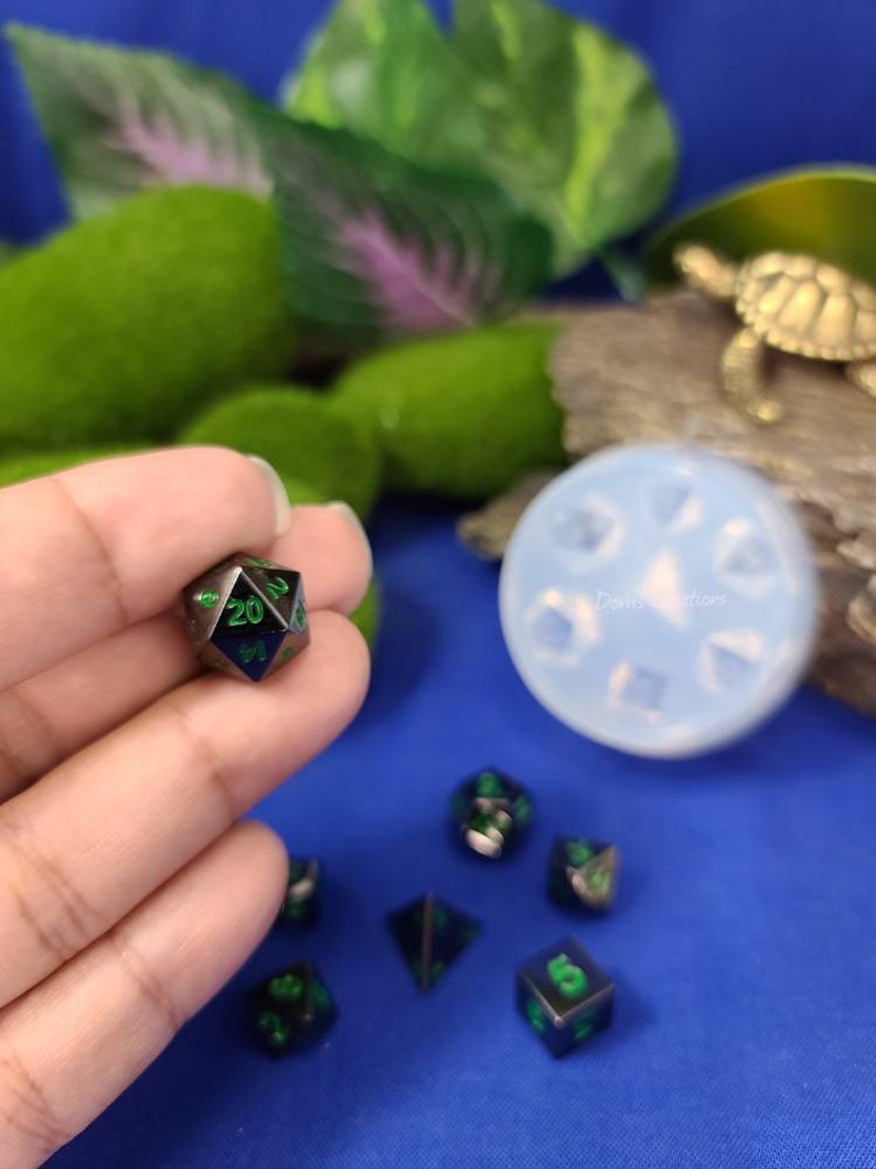 May include: A set of black and green dice with green numbers. The dice are on a blue surface.