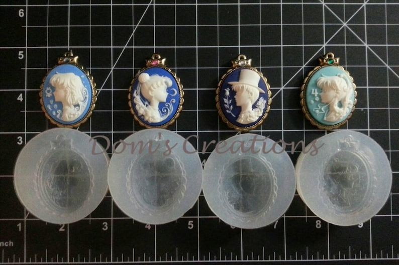 May include: Four cameo-style pendants with gold frames and blue, green, and white enamel. The pendants feature a white silhouette of a person's head and shoulders. The pendants are displayed on a white grid background with four clear silicone molds.
