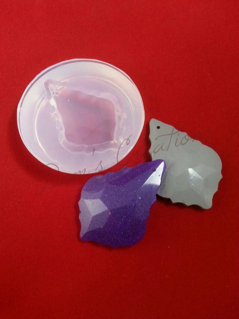 May include: A clear silicone mold for making resin jewelry. The mold is shaped like a leaf with a pointed tip. Two finished resin pieces are shown, one purple and one gray.