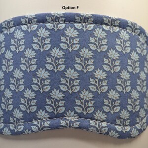 K&ouml;nnte beinhalten: Eine blaue Augenmaske mit einem Blumenmuster in Hellblau und Braun. Die Maske hat eine gebogene Form und ist an den R&auml;ndern gen&auml;ht. Der Text "Option F" steht oben.
