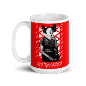 Könnte beinhalten: Weiße Keramiktasse mit rotem Hintergrund und einem Schwarzweißbild einer amerikanischen Ureinwohnerin mit den Worten "RESPECT UPRISING INDIGENOUS" auf der Tasse.