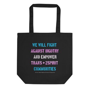May include: Black tote bag with the text "WE WILL FIGHT AGAINST BIGOTRY AND EMPOWER TRANS+2SPIRIT COMMUNITIES" in blue and pink lettering. The text "R.L.S.E.: Radical Indigenous Services & Empowerment" is in smaller white lettering at the bottom.