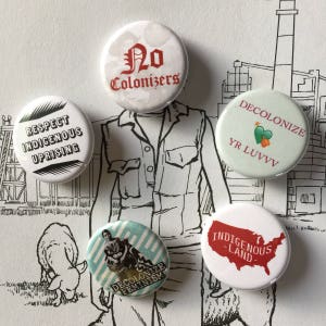 May include: Five round white button pins with different messages and designs. The pins feature the following text: "No Colonizers", "Respect Indigenous Uprising", "Decolonize Yr Luvv", "Decolonize Feminism", and "Indigenous Land".