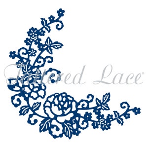 May include: A blue die-cut floral corner design with a large rose and smaller flowers and leaves. The design is from the company "Tattered Lace".