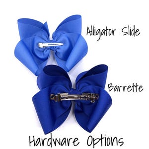 Pu&ograve; includere: Due fiocchi per capelli blu con diverse opzioni hardware. Un fiocco ha una clip a coccodrillo, l'altro una forcina. &Egrave; visibile anche il testo "Alligator Slide", "Barrette" e "Hardware Options".