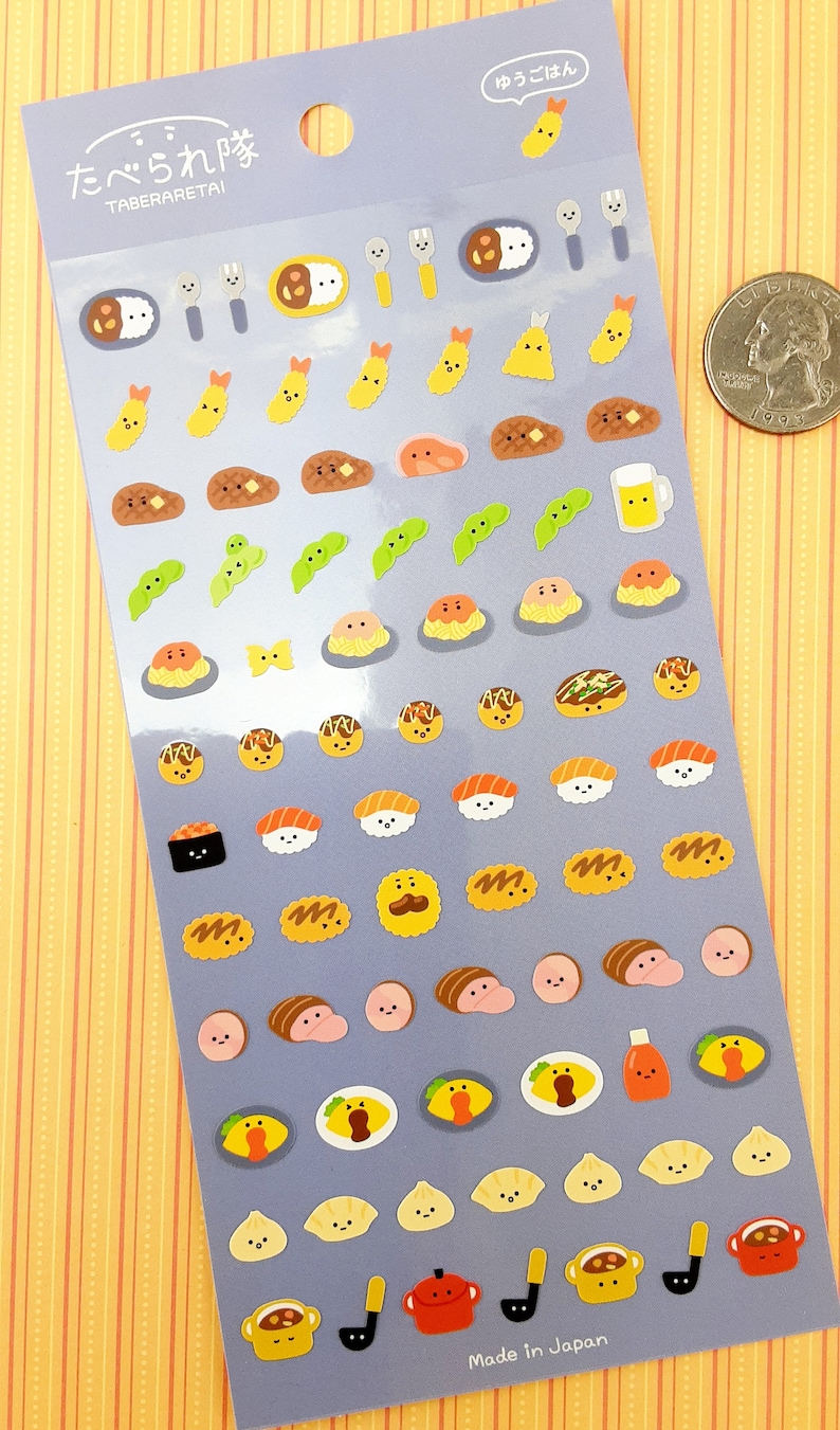 May include: A sheet of colorful stickers featuring various Japanese foods, including sushi, ramen, curry rice, and edamame. The stickers are on a light blue background with the text "Taberaretai" and "Made in Japan".