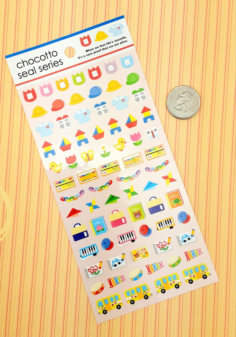 May include: A sheet of colorful stickers featuring various images related to preschool and early childhood education. The stickers include images of hats, uniforms, building blocks, crayons, a butterfly, a duck, a book, a piano, a drum, and a school bus. The text "chocotto seal series" is printed at the top of the sheet.