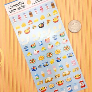 May include: A sheet of colorful stickers featuring various food items, including cheese, pizza, ice cream, and desserts. The stickers are on a blue background with white borders. The text "chocotto seal series" is printed in black at the top of the sheet. The text "When we feel life's warmth, it's a sure proof that we are alive." is printed in black at the top of the sheet.