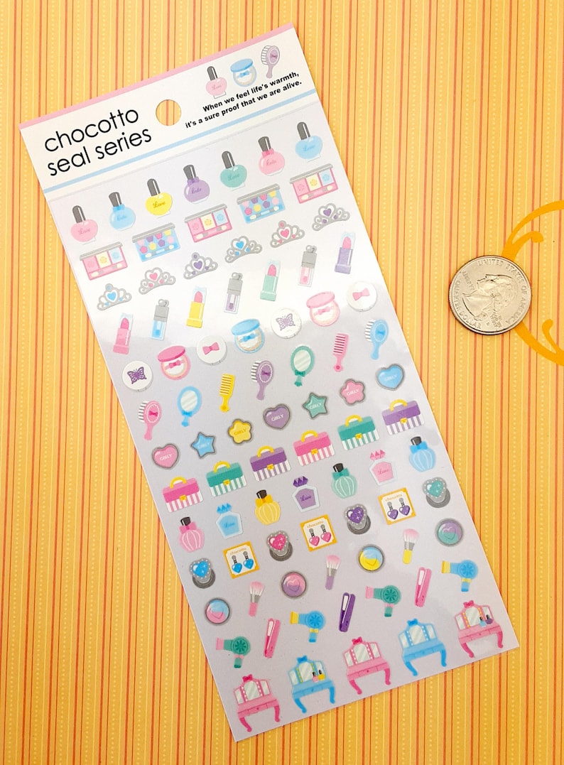 May include: A sheet of colorful stickers featuring various beauty and makeup themed illustrations. The stickers include nail polish bottles, makeup palettes, lipstick tubes, perfume bottles, hairbrushes, mirrors, and a vanity set. The sheet is labeled "chocotto seal series" and includes the text "When we feel life's warmth, it's a sure proof that we are alive."