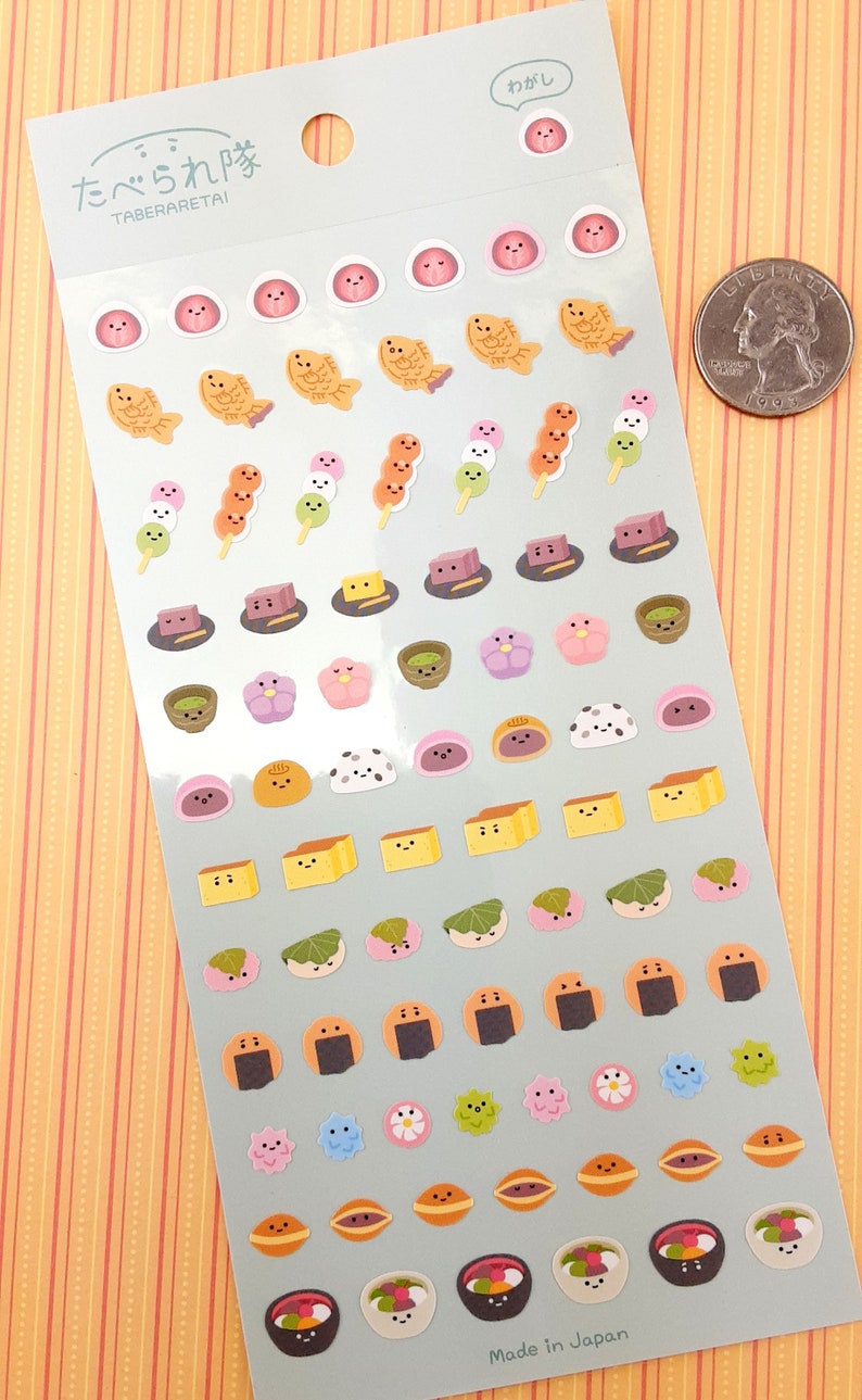 May include: A sheet of Japanese food themed stickers with a variety of colorful designs. The stickers feature cute faces and include items like fish cakes, mochi, dango, and rice balls. The sheet is labeled "Taberaretai" which means "I want to eat it" in Japanese.