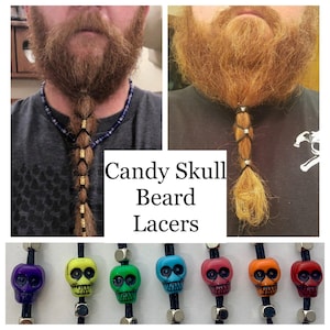 May include: A set of six colorful skull beard beads. The beads are made of plastic and have a candy skull design. The beads are strung on black elastic cord. The beads are available in purple, yellow, green, blue, red, and orange.