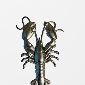 May include: A silver metal lobster figurine with detailed claws and a shiny finish.