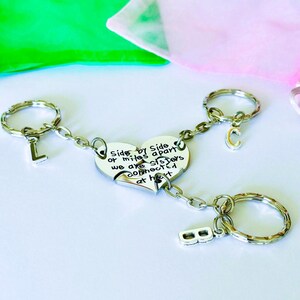 May include: Silver-toned keychain set with a heart-shaped pendant that reads "Side by Side or miles apart we are sisters connected at heart." Each keychain has a letter: L, C, and B.