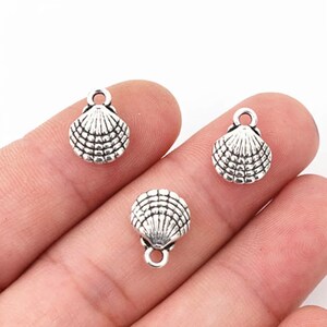 May include: Three silver-toned metal seashell charms with a loop for attaching to jewelry or crafts.