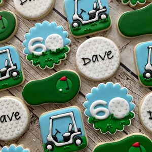 May include: A set of 10 golf-themed sugar cookies decorated with green, blue and white icing. The cookies feature golf balls, golf carts and the number 60. Some cookies also have the name "Dave" written on them.