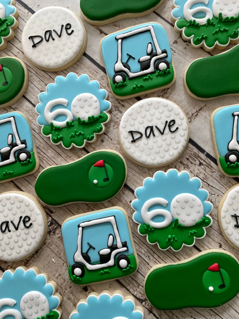 May include: A set of 10 golf-themed sugar cookies decorated with green, blue and white icing. The cookies feature golf balls, golf carts and the number 60. Some cookies also have the name "Dave" written on them.
