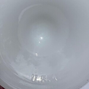 May include: A white, opaque glass object with a rounded shape. The letters "U.S.A." are embossed on the bottom of the object. The object has a smooth, glossy surface.
