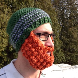 May include: A green and purple crocheted hat with a matching orange crocheted beard. The hat has a striped pattern and the beard is a solid color.