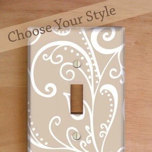 May include: Three light switch and outlet covers with a beige background and white swirl design. The covers are labeled "Standard Cover", "Decora/Rocker Cover", and "Outlet Cover".