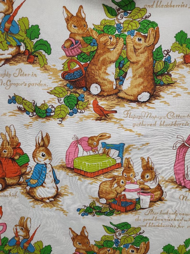 May include: A white fabric with a repeating pattern of bunnies and blueberries. The bunnies are brown and white with pink noses. The blueberries are blue and green. The fabric has the text "The Tale of Peter Rabbit" printed on it.
