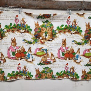 May include: White fabric with a repeating pattern of bunnies and text. The text reads "Peter had only a spoonful of the good brown bread and milk with bread and blackberries for supper." and "Naughty Peter in Mrs. McGregor's garden".
