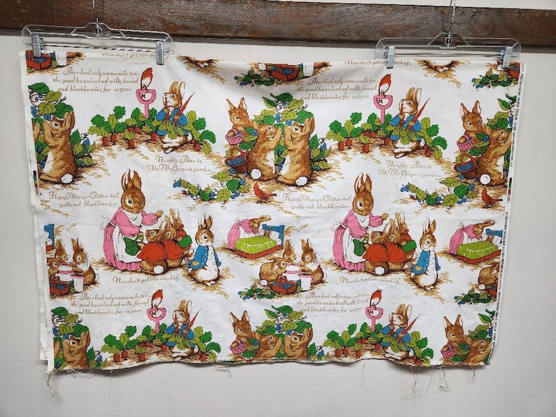 May include: White fabric with a repeating pattern of bunnies and text. The text reads "Peter had only a spoonful of the good brown bread and milk with bread and blackberries for supper." and "Naughty Peter in Mrs. McGregor's garden".