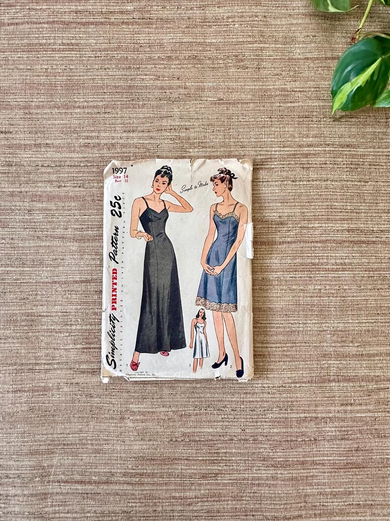 May include: Vintage Simplicity printed sewing pattern 1997, size 14, bust 32. The pattern features illustrations of two slip dresses. The cover is off-white with black text and illustrations. The dress on the left is a long, dark dress, and the dress on the right is a blue dress.