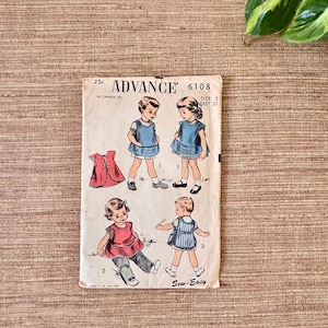 May include: Vintage Advance sewing pattern 6108 for children's clothing. The pattern features illustrations of children in various outfits, including dresses and tops. The cover is aged with text that reads "Sew-Easy".