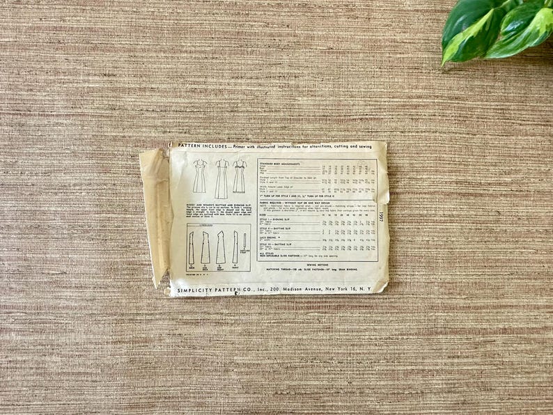 May include: Vintage Simplicity sewing pattern on a textured surface. The pattern includes illustrations of dresses and detailed instructions. The pattern is from Simplicity Pattern Co., Inc., located in New York.