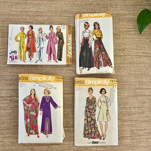 May include: Four vintage sewing patterns featuring illustrations of women's clothing designs. The patterns include designs for dresses, jumpsuits, and other garments. The patterns are labeled with the brands "Jiffy" and "Simplicity".