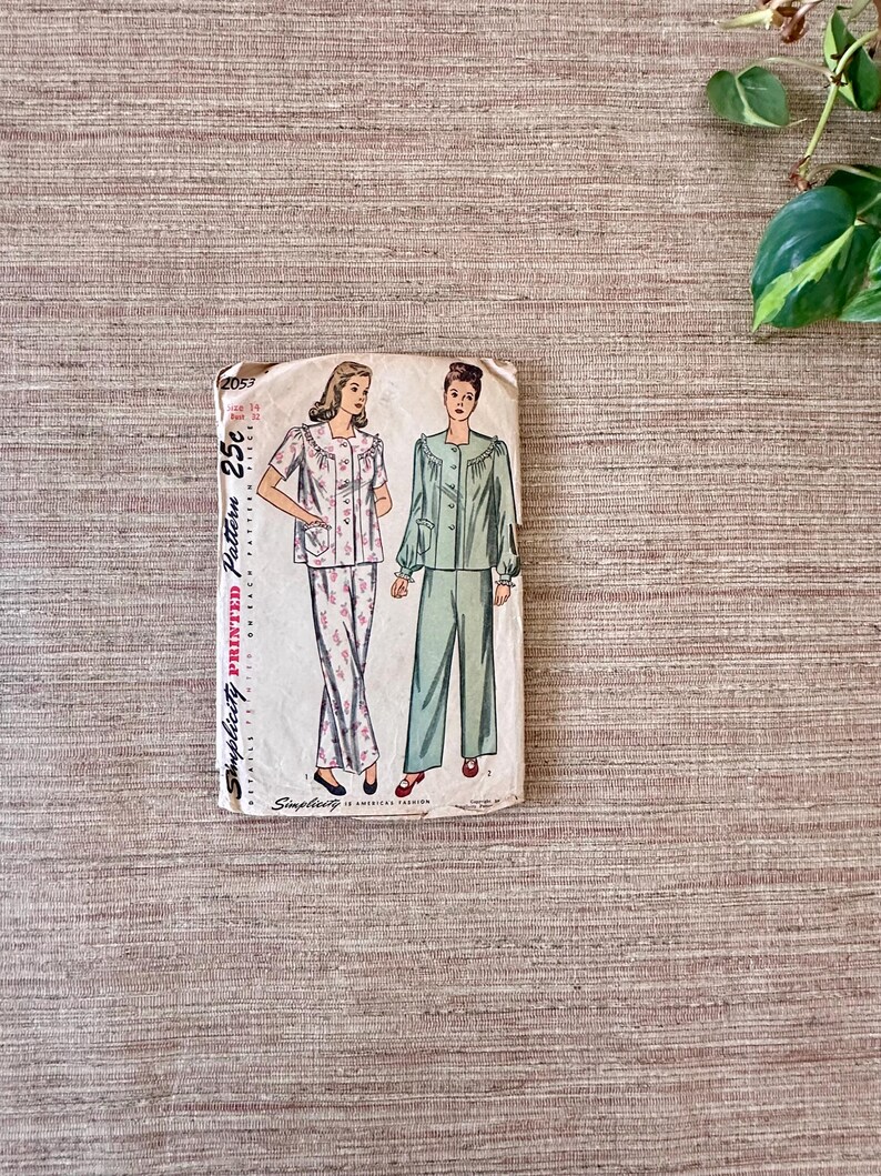 May include: Vintage Simplicity printed pattern for pajamas. The pattern envelope features illustrations of pajama sets, one with floral print pants and the other in solid green. The envelope reads "Simplicity Printed Pattern" and "25&cent;".