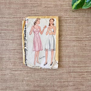 May include: Vintage Simplicity 15&cent; Pattern envelope featuring illustrations of two women in lingerie. One woman is in a pink slip dress, the other in a white bra and skirt. The envelope is yellowed with age.