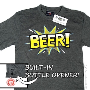 May include: A dark gray t-shirt with a yellow and blue comic book style "BEER!" graphic. The shirt has a built-in bottle opener on the side seam. The shirt has a small tag with the words "Middle Cat Clothing" on it.