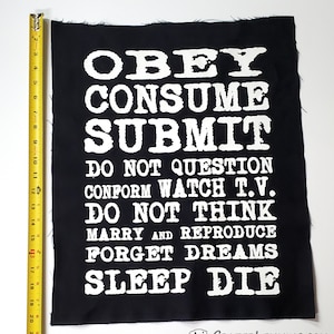 May include: Black fabric patch with white text that reads "Obey Consume Submit Do Not Question Conform Watch T.V. Do Not Think Marry and Reproduce Forget Dreams Sleep Die".