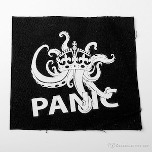 Peut inclure: Patch thermocollant noir et blanc avec une pieuvre blanche portant une couronne et le mot "PANIC" en dessous.