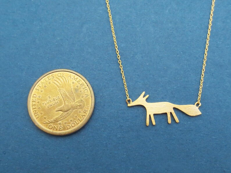 Pu&ograve; includere: Una collana con catena dorata con un ciondolo a forma di volpe. Il ciondolo &egrave; una semplice silhouette di una volpe con una lunga coda.