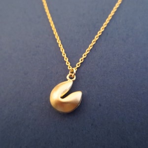May include: A gold chain necklace with a gold fortune cookie charm.