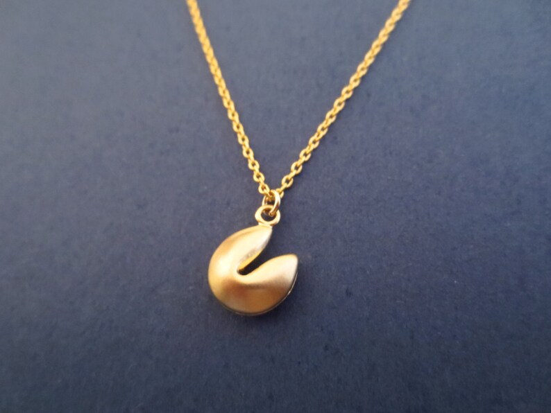May include: A gold chain necklace with a gold fortune cookie charm.