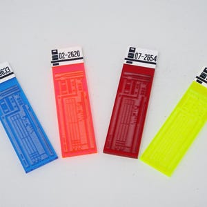 May include: Four colourful plastic strips with black text and numbers. The strips are blue, orange, red, and yellow. The numbers on the strips are 56-9633, 02-2620, 07-2654, and 97-8590.