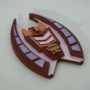May include: A brown, pink and gold 3D printed ornament shaped like a spaceship with a geometric design.