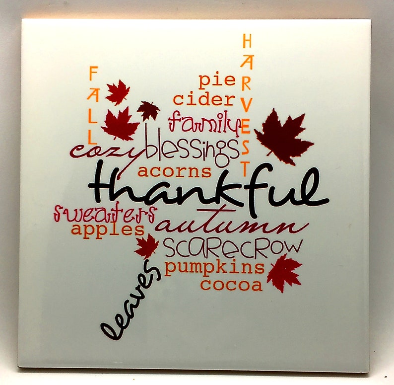 Puede incluir: Azulejo de cer&aacute;mica blanco con un dise&ntilde;o de arte de palabras con tem&aacute;tica oto&ntilde;al. Las palabras "Fall", "Thankful", "Autumn", "Sweaters", "Apples", "Leaves", "Pie", "Cider", "Family", "Blessings", "Acorns", "Scarecrow", "Pumpkins" y "Cocoa" est&aacute;n dispuestas en forma de hoja.