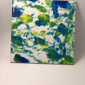 Puede incluir: Un azulejo de cer&aacute;mica cuadrado con fondo blanco y salpicaduras abstractas de pintura azul y verde.