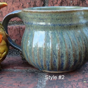 Könnte beinhalten: Drei Keramikkrüge in verschiedenen Stilen. Der erste Krug ist orange und braun mit einem Blumendesign. Der zweite Krug ist blau und grün mit einem gestreiften Design. Der dritte Krug ist braun mit einem gewellten Design.